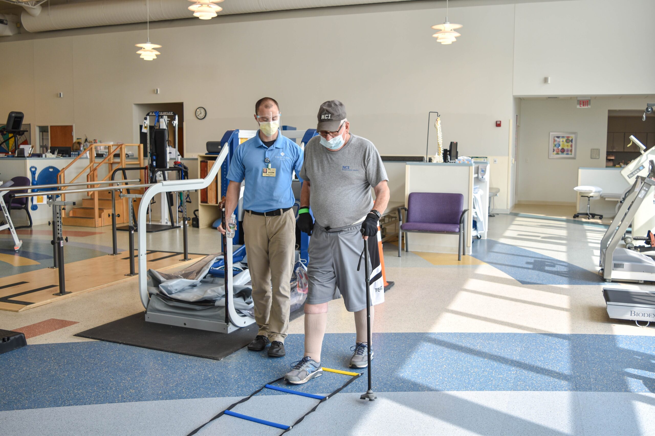 Fisher-Titus patient Danny Weisenburger stepping through a rope ladder with the help of his physical therapist