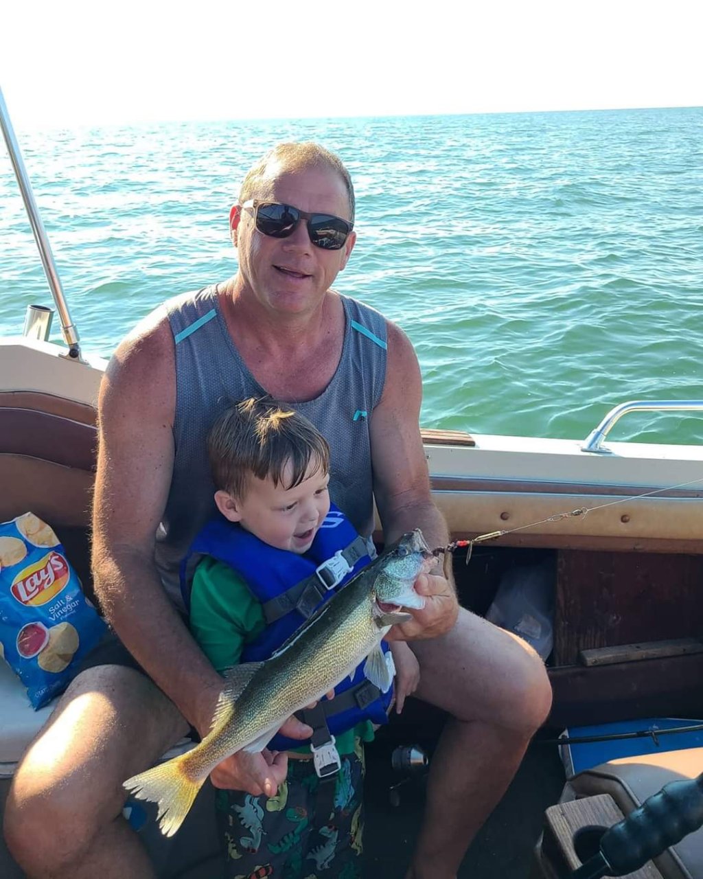 Jim with his son on his boat on a lake