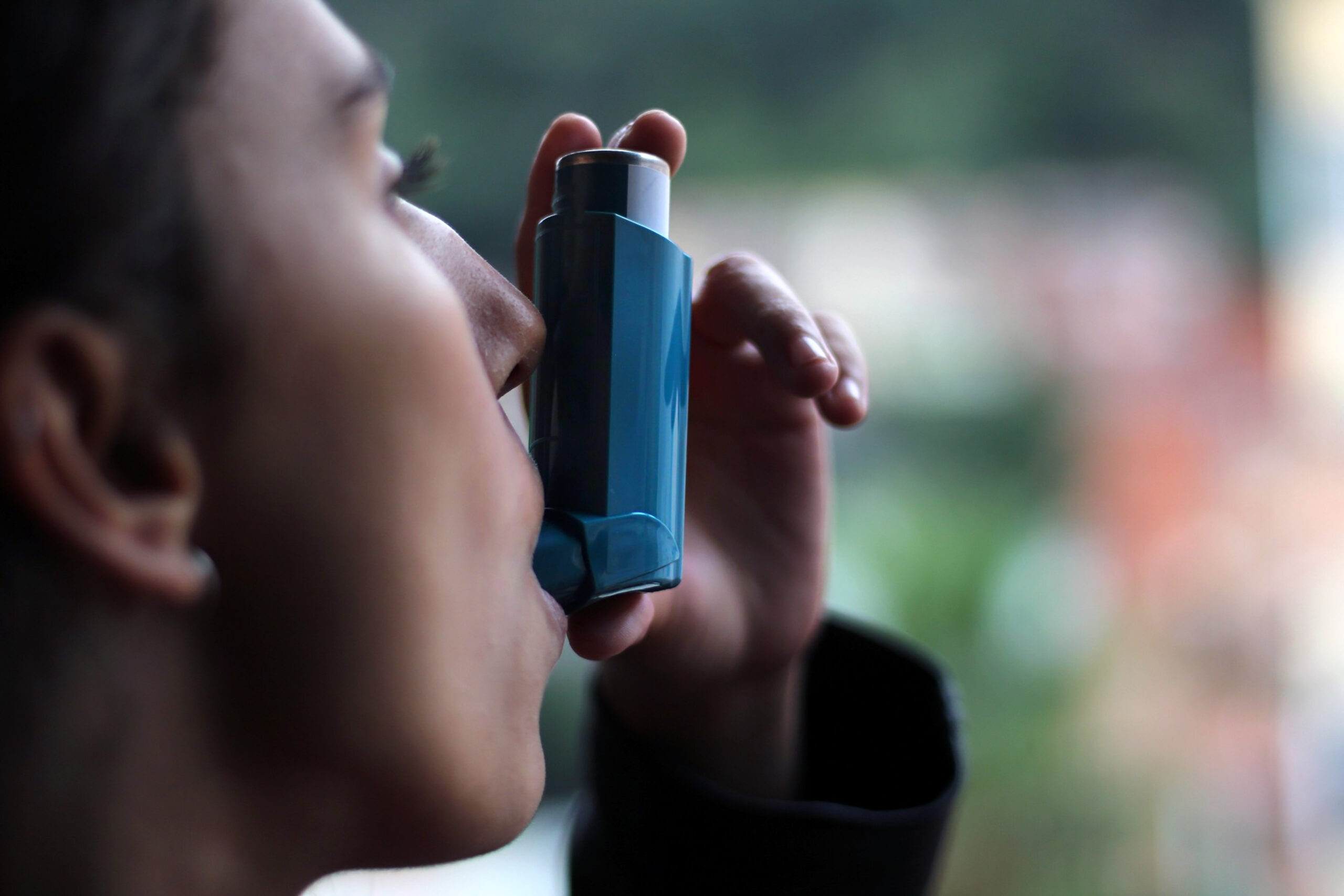 Person using a blue metered-dose inhaler