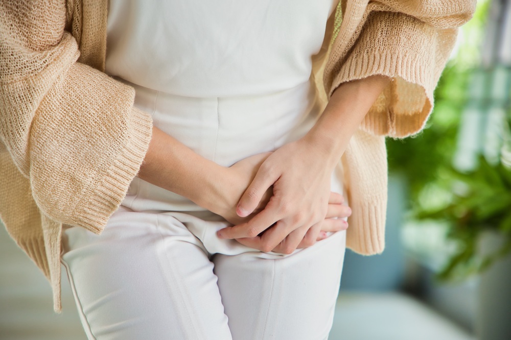 Woman holding her lower abdomen, illustrating urinary incontinence or urinary tract infection discomfort.